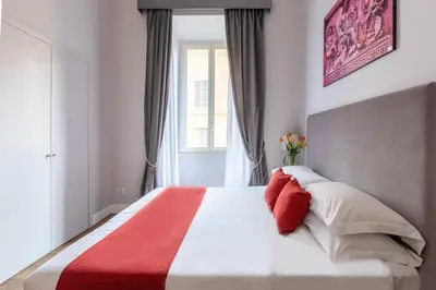 a bedroom with a large bed with red and white pillows at Spagna Art & Suites - CA Domus Collection in Rome