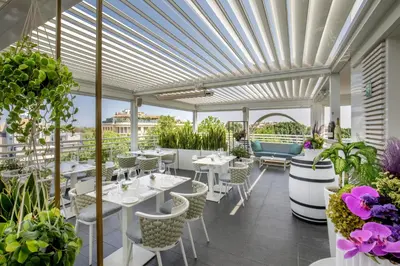 a restaurant with white tables and chairs and plants at The Tribune, part of JdV by Hyatt in Rome