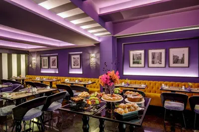 a dining room with tables and chairs with food on them at The Tribune, part of JdV by Hyatt in Rome