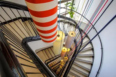 a spiral staircase with a red and white pole at The Tribune, part of JdV by Hyatt in Rome