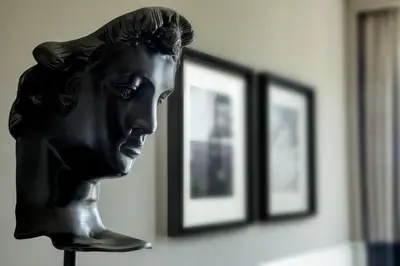 a bronze bust of a woman in front of framed pictures at The Tribune, part of JdV by Hyatt in Rome