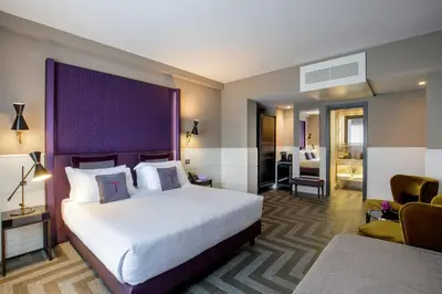 a hotel room with a large bed with a purple headboard at The Tribune, part of JdV by Hyatt in Rome