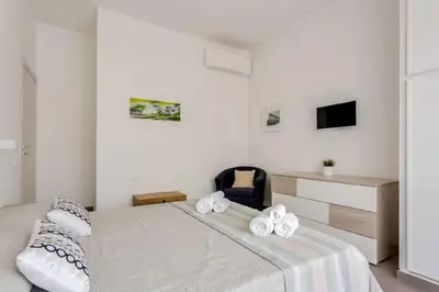 a white bedroom with a bed and a chair at Franca's Home in Rome