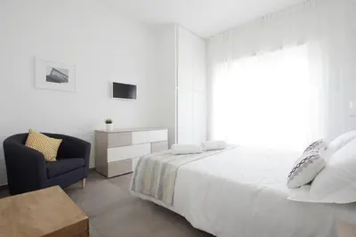 a white bedroom with a bed and a chair at Franca's Home in Rome