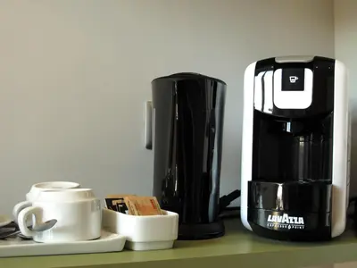 a coffee maker and coffee cups on a counter at Roma Veneto Relais in Rome