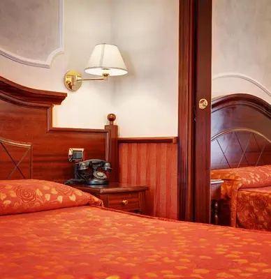 a hotel room with two beds and a lamp at Hotel Best Roma in Rome
