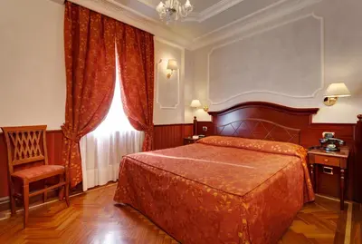 a bedroom with a bed and a chair and a window at Hotel Best Roma in Rome