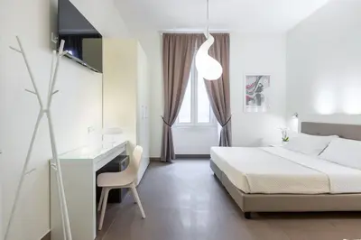 a white bedroom with a bed and a desk at Maison Trevi in Rome