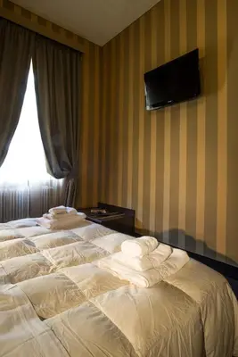 two beds in a hotel room with a television on the wall at AS Planet in Rome