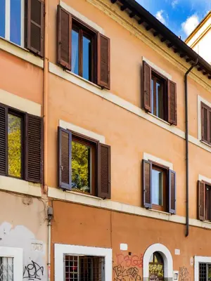 an orange building with brown shuttered windows at River View Apartment in Rome
