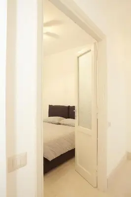 a white bedroom with a bed and a mirror at Testaccio Old Rome Apartment in Rome