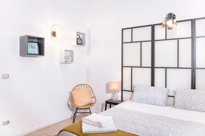 a white bedroom with a bed and a chair at Interno 6 San Pietro in Rome