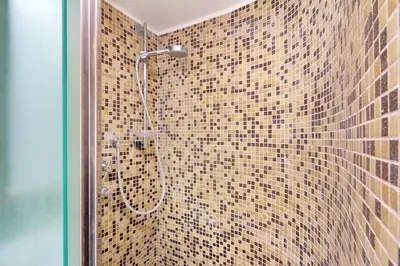 a bathroom with a shower with a tiled wall at Frattina Family Romantic Superior Suite in Rome