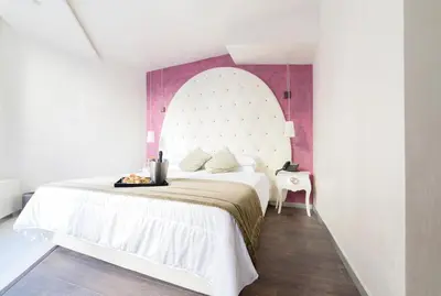 a bedroom with a white bed and a pink wall at Hotel Vespasiano in Rome