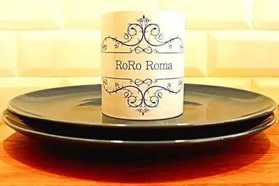 a coffee cup sitting on top of a black plate at RoRo Roma in Rome