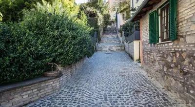 a cobblestone alley with a building and a hedge at Le Scalette in Rome