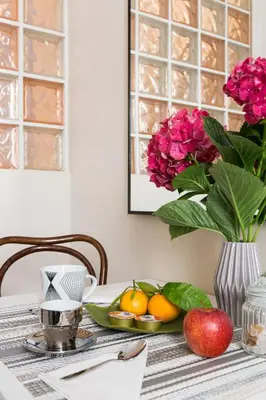 a table with a vase of flowers and fruit on it at Dandy Suite in Rome