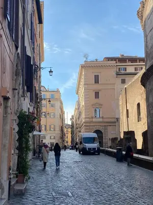 a group of people walking down a cobblestone street at A Window on Pantheon in Rome