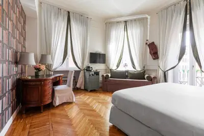 a bedroom with a bed and a desk and curtains at Relais Donna Lucrezia in Rome
