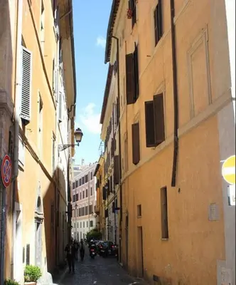 an alley with buildings and people walking down the street at Lupa Flat in Rome