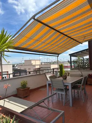 a patio with a table and chairs on a roof at Appartamento con Terrazza vicino Gemelli e Vaticano in Rome