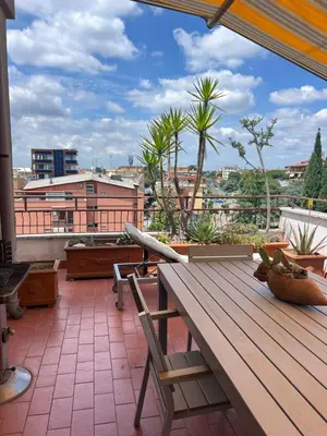 a patio with a wooden table and chairs on a balcony at Appartamento con Terrazza vicino Gemelli e Vaticano in Rome