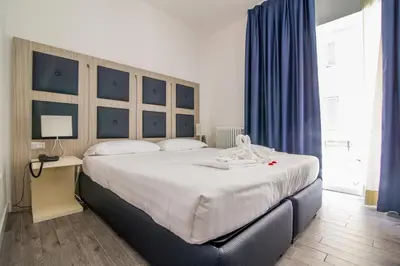 a bedroom with a large white bed with blue curtains at Vatican Relais Rome in Rome