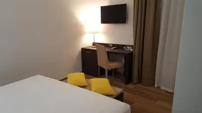 a hotel room with a bed and a desk with two yellow chairs at Una Finestra su Monti in Rome