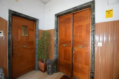 two wooden doors in a hallway with a potted plant at The Voice of the Pope in Rome