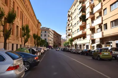 a street with cars parked on the side of the road at The Voice of the Pope in Rome