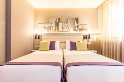 two beds in a bedroom with yellow and purple pillows at Orazio Palace Hotel in Rome