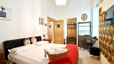 a bedroom with a white bed with a red chair at Festina Lente in Rome