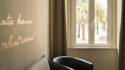 a room with a chair and a window with palm trees at Domus Corsini in Rome