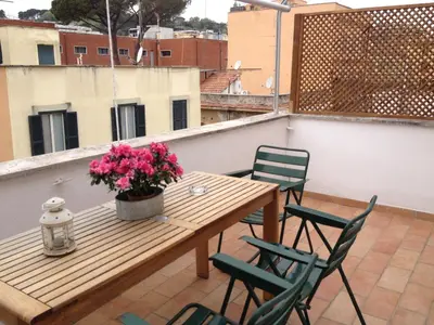 a wooden table and chairs on a balcony with flowers at L'Attichetto di Ponte Milvio a Roma Centro in Rome