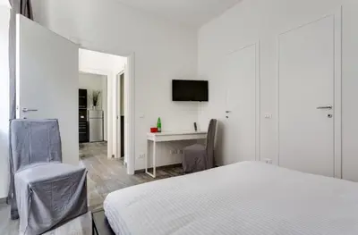 a white bedroom with a bed and a desk at Porta Latina Suite - Private Apartment Rome's Center in Rome