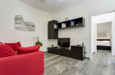 a living room with a red couch and a television at Porta Latina Suite - Private Apartment Rome's Center in Rome