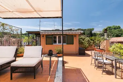a patio with chairs and a table and an umbrella at Trastevere Charming Penthouse in Rome