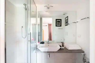 a white bathroom with a sink and a shower at Trastevere Charming Penthouse in Rome