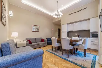 a living room with a blue couch and a table and chairs at 900 Apartments Lazio, Emilia & La Corte in Rome