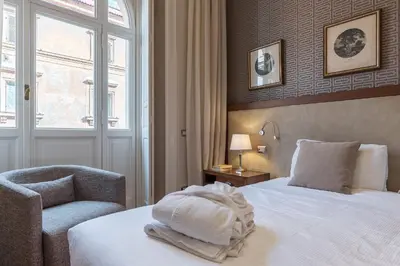 a bedroom with a bed and a chair and a window at 900 Apartments Lazio, Emilia & La Corte in Rome