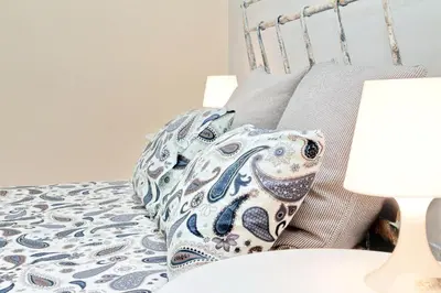 a bed with a blue and white pillow on it at Le 2 Basiliche - Esquilino Retreat in Rome