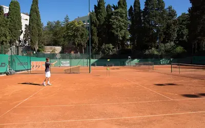 a man is playing tennis on a tennis court at LH Hotel Excel Roma Montemario in Rome