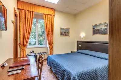 a bedroom with a bed and a desk and a table and a desk at Locanda San Cosimato in Rome