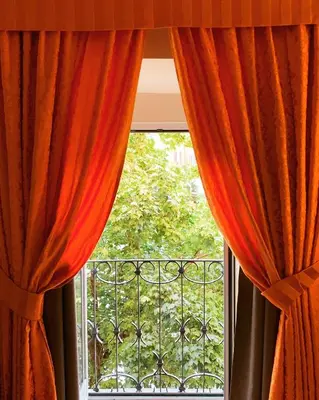 a window with orange curtains and a balcony at Locanda San Cosimato in Rome