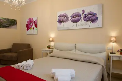 a bedroom with a bed and a chair and flowers at House Gregorio in Rome