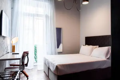 a bedroom with a bed and a desk and a window at Boutique Centrale Palace Hotel in Rome