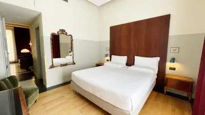 a bedroom with a large white bed and a mirror at Vino e Oli Residenze in Rome