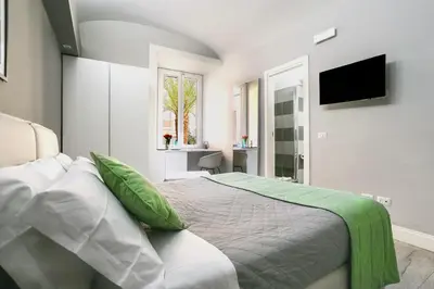a bedroom with a bed with green pillows and a television at Scipioni Best Rooms in Rome