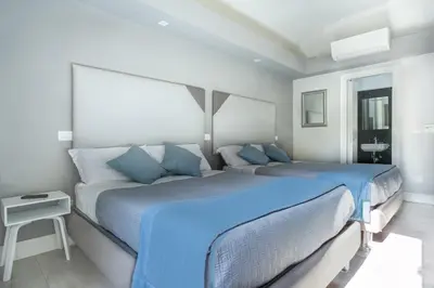 two beds in a white room with blue pillows at Scipioni Best Rooms in Rome