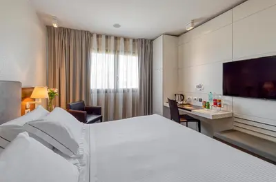 a hotel room with a large bed and a desk at H10 Roma Città in Rome